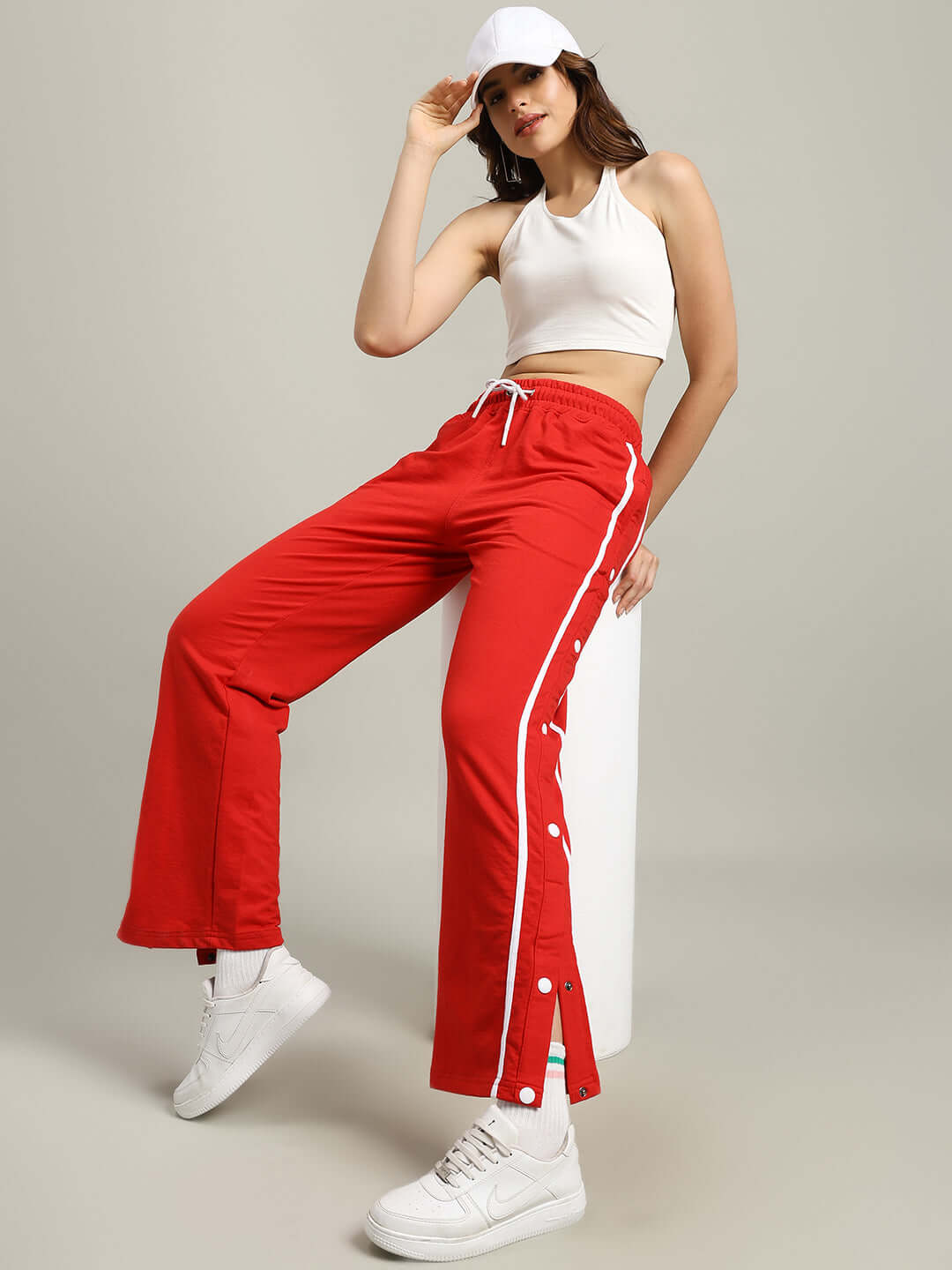 Model wearing WOMEN'S CONTRAST PANEL JOGGERS RED with white sneakers and crop top, highlighting trendy style.