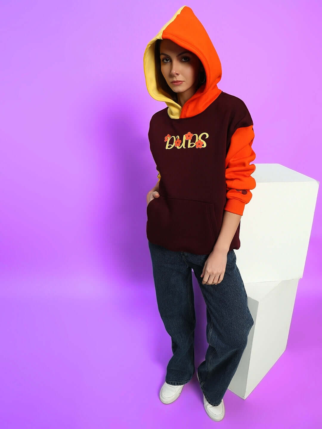 Woman wearing Women's Cosmos Oversized Fleece Hoodie in vibrant multi-color design against a purple background.