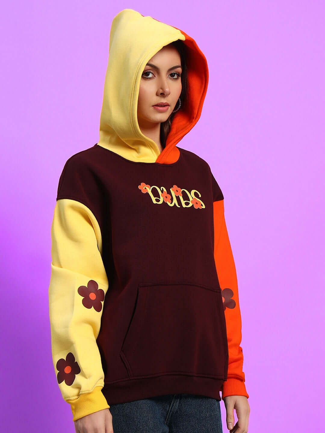 Model wearing Women's Cosmos Oversized Fleece Hoodie in multi-colored design with floral accents, showcasing vibrant style.