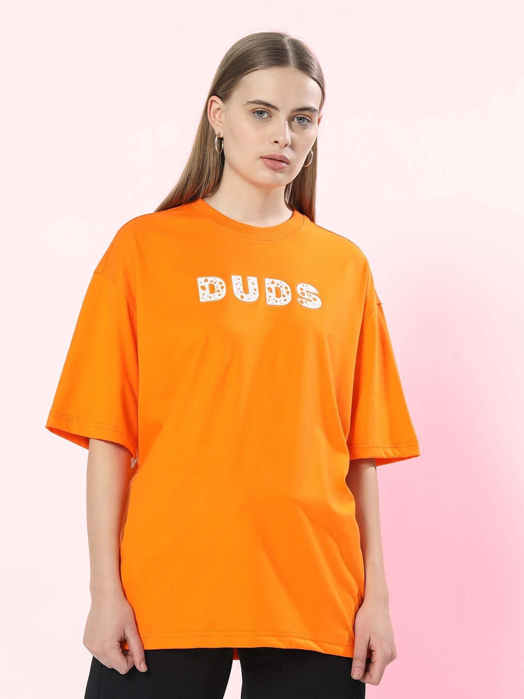 Woman wearing an orange oversized DUDS t-shirt with "Courage" design, perfect for a bold and comfortable look.