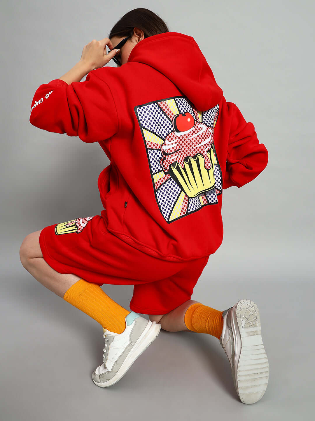 Model wearing WOMEN CUPCAKE FLEECE CO-ORD RED with artistic cupcake design on the back, showcasing trendy, vibrant streetwear.