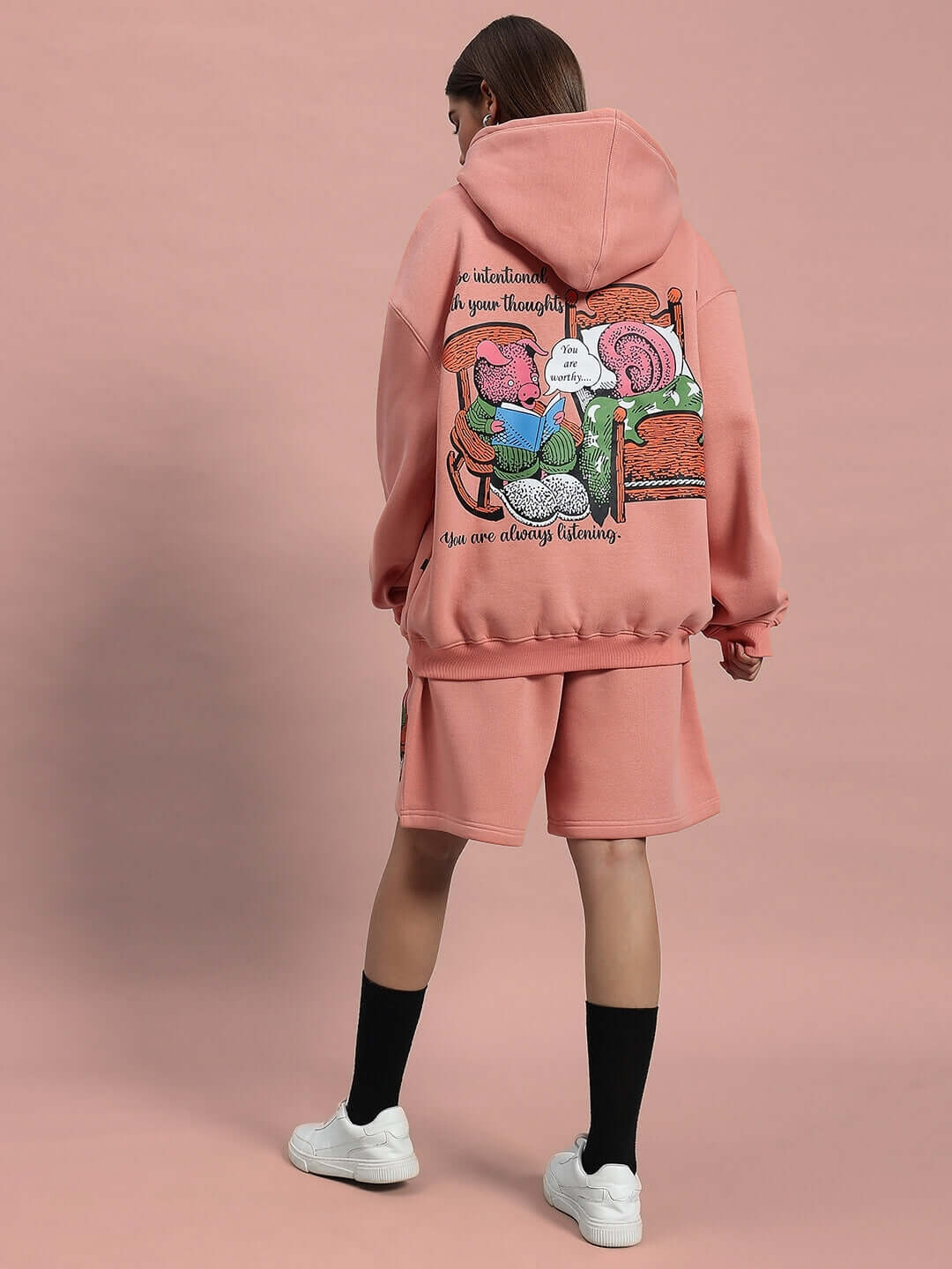 Woman wearing WOMEN DELIBERATE FLEECE SHORTS PEACH with matching hoodie, showcasing comfort and style.