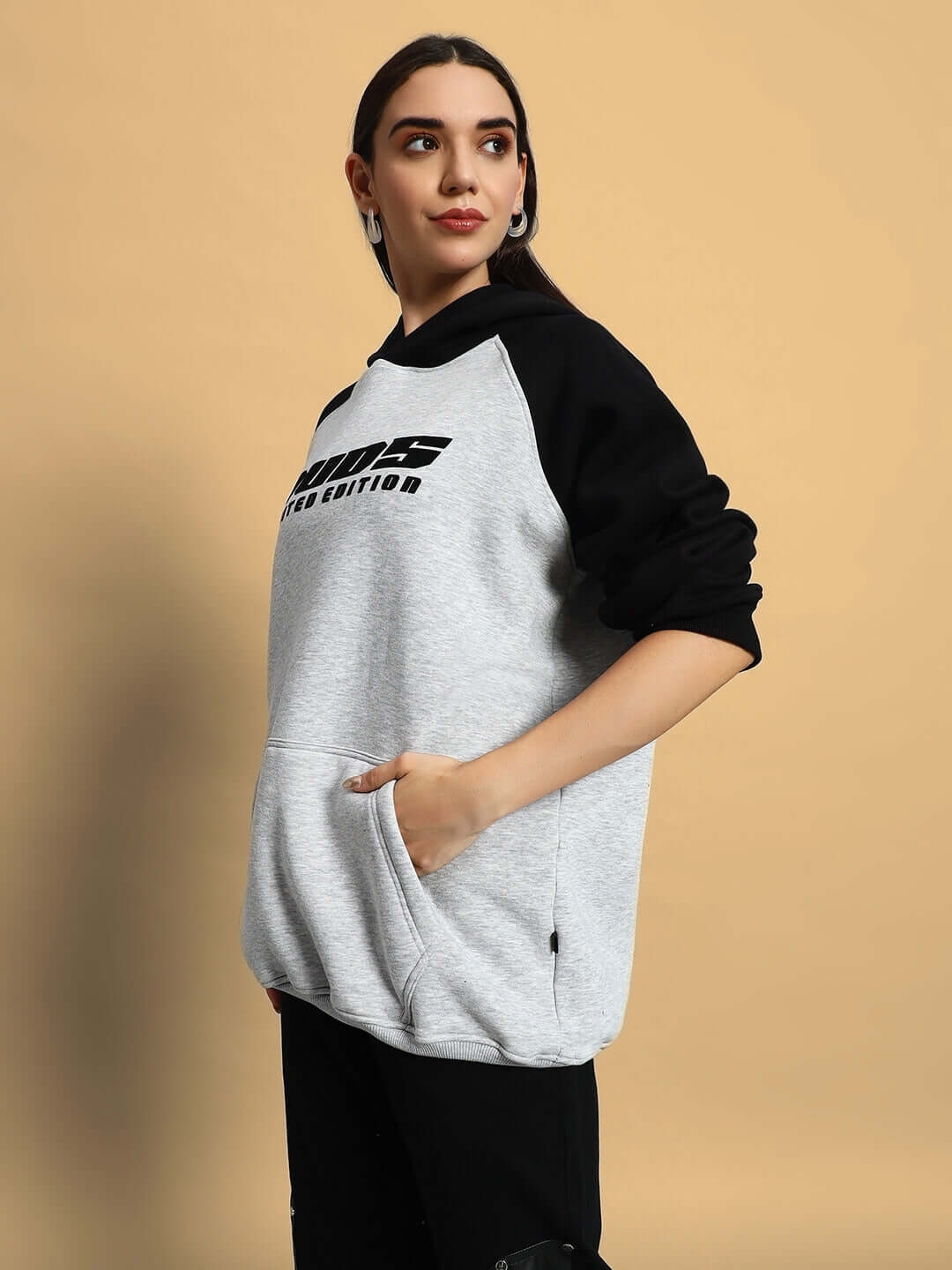 Woman wearing WOMEN DELUXE FLECCE OVERSIZE HOODIE BLACK MELANGE GREY, showcasing streetwear style with comfort and warmth.
