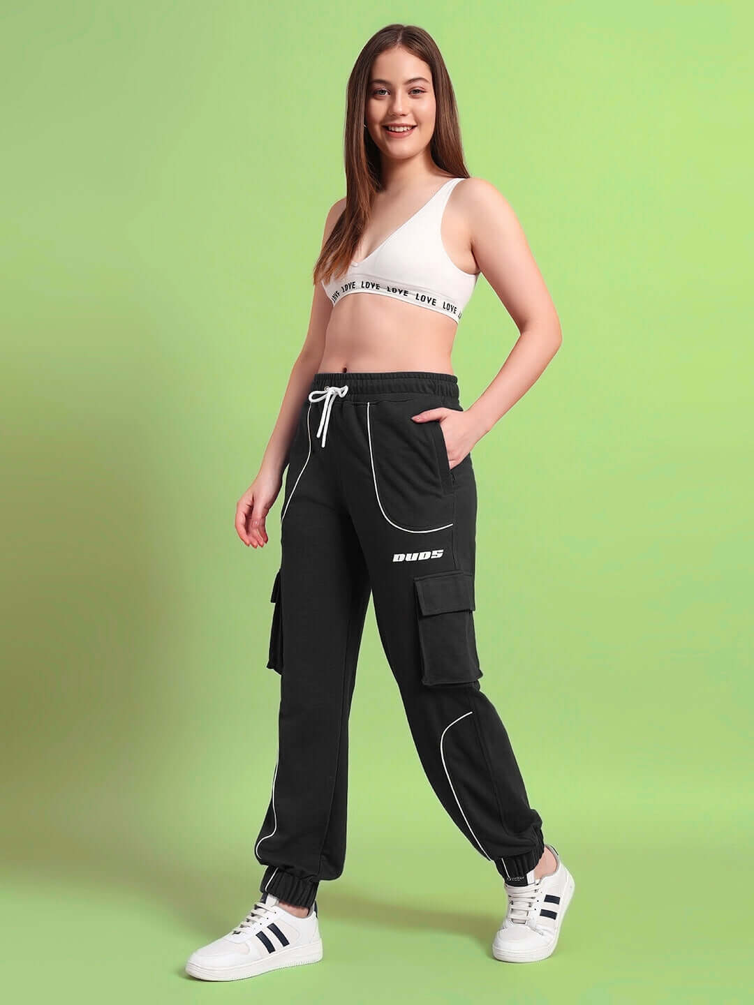 Woman wearing WOMENS DEVENO RELAXED-FIT JOGGERS BLACK in a stylish pose on green background.
