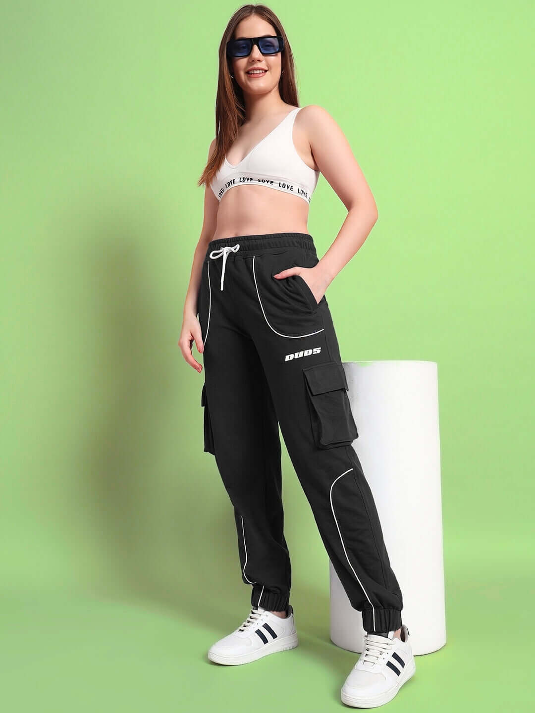 Woman wearing WOMENS DEVENO RELAXED-FIT JOGGERS BLACK standing against green background.