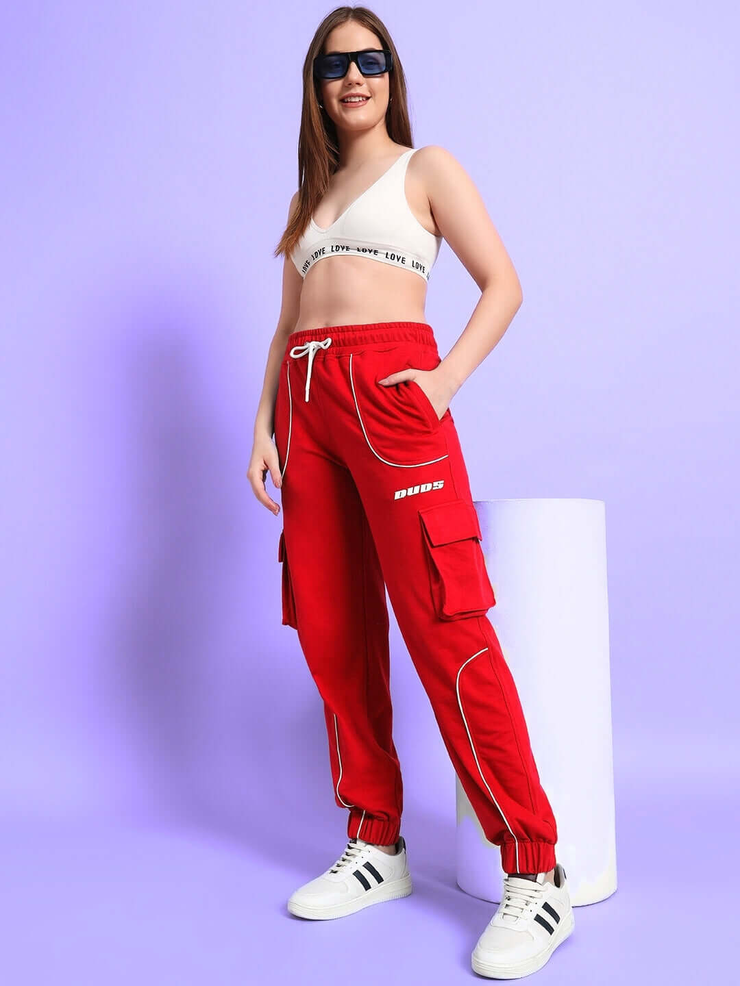 Woman wearing women's Deveno relaxed-fit red joggers with sunglasses, showcasing sporty casual fashion by DUDS.