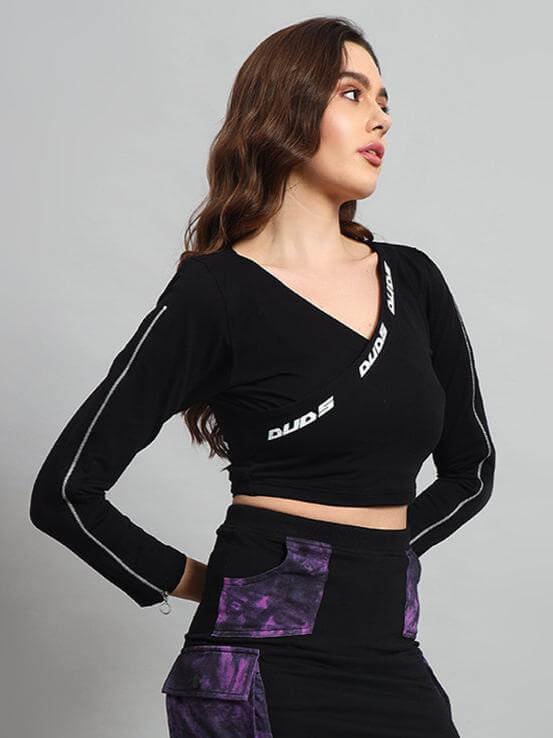 Woman modeling black-purple tie-dye crop top made of cotton lycra with long sleeves, showcasing side view. Fashionable and versatile style.