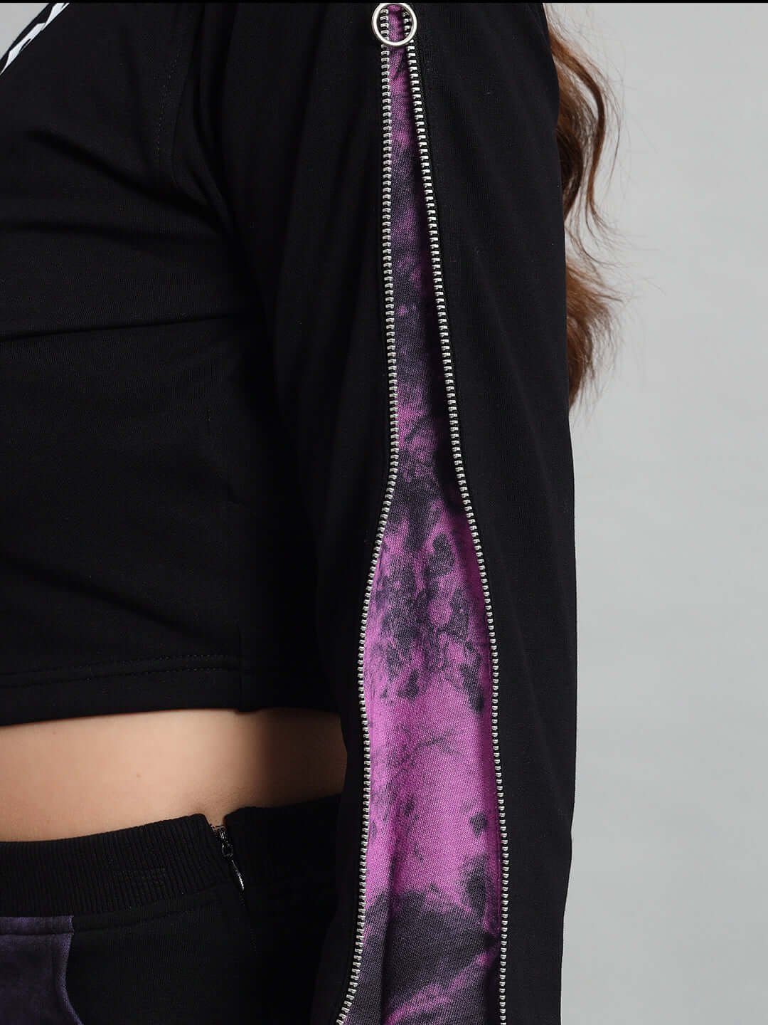 Close-up of a women's black and purple tie-dye crop top sleeve with zipper detail, made from premium cotton lycra fabric.