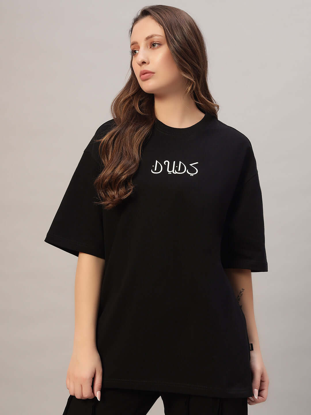 Woman wearing a black oversized t-shirt made of premium heavy gauge fabric featuring a logo, crafted from 97% cotton with 3% elastane.