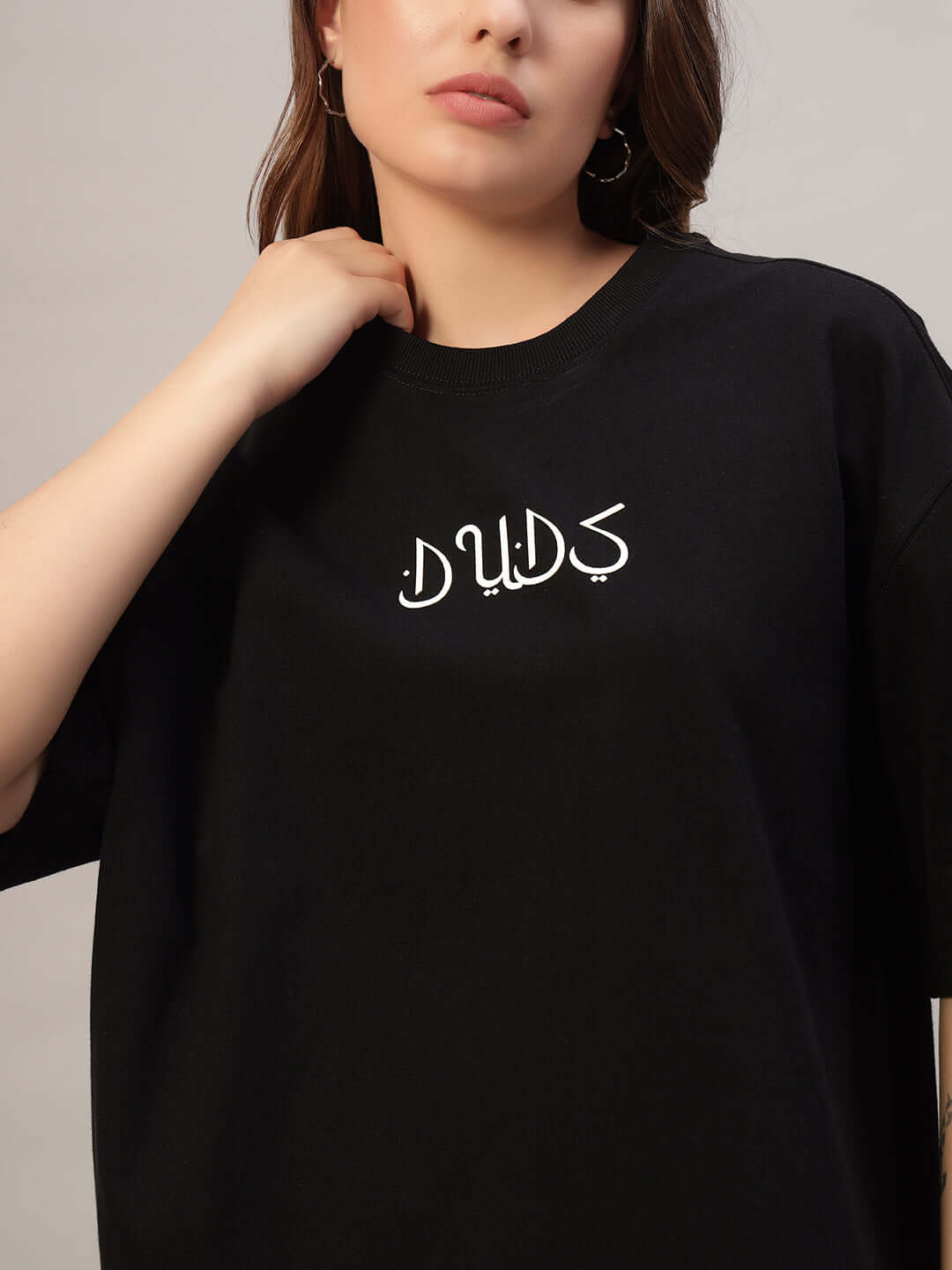 Woman wearing black oversized t-shirt made from premium cotton, featuring stylish graphic design on front.