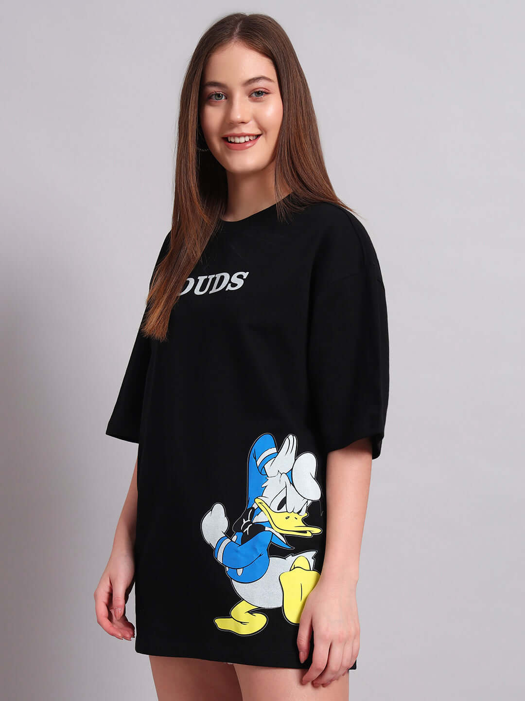 Woman wearing a black oversized T-shirt featuring a Donald Duck print, made from premium heavy gauge cotton fabric. Country of origin: India.