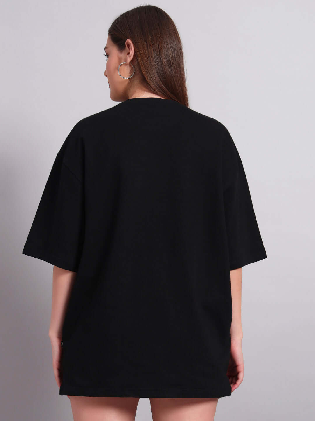 Woman wearing black Donald Duck printed oversized T-shirt, back view. Premium cotton fabric, perfect for casual wear. Made in India.