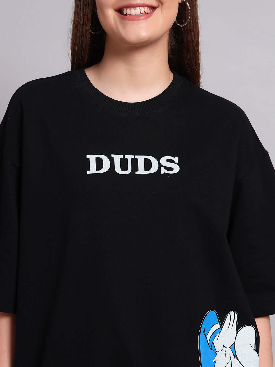 Black oversized t-shirt featuring Donald Duck print and 'DUDS' text, made from premium cotton blend. Ideal for stylish casual wear.