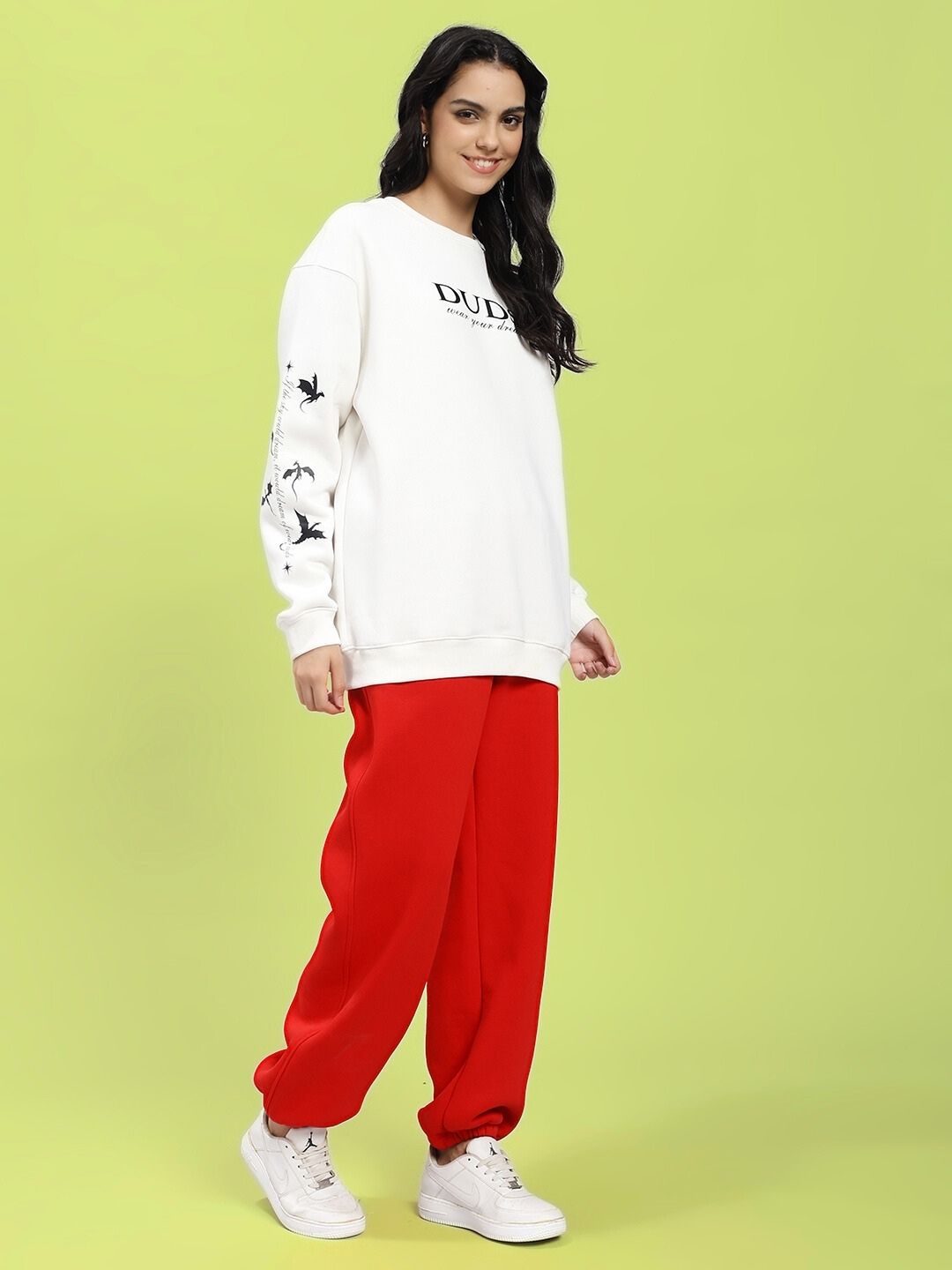 Model wearing WOMEN FLY OR DIE DRAGON PRINT FLEECE COORD OFF WHITE RED with dragon print detail in urban style pose.
