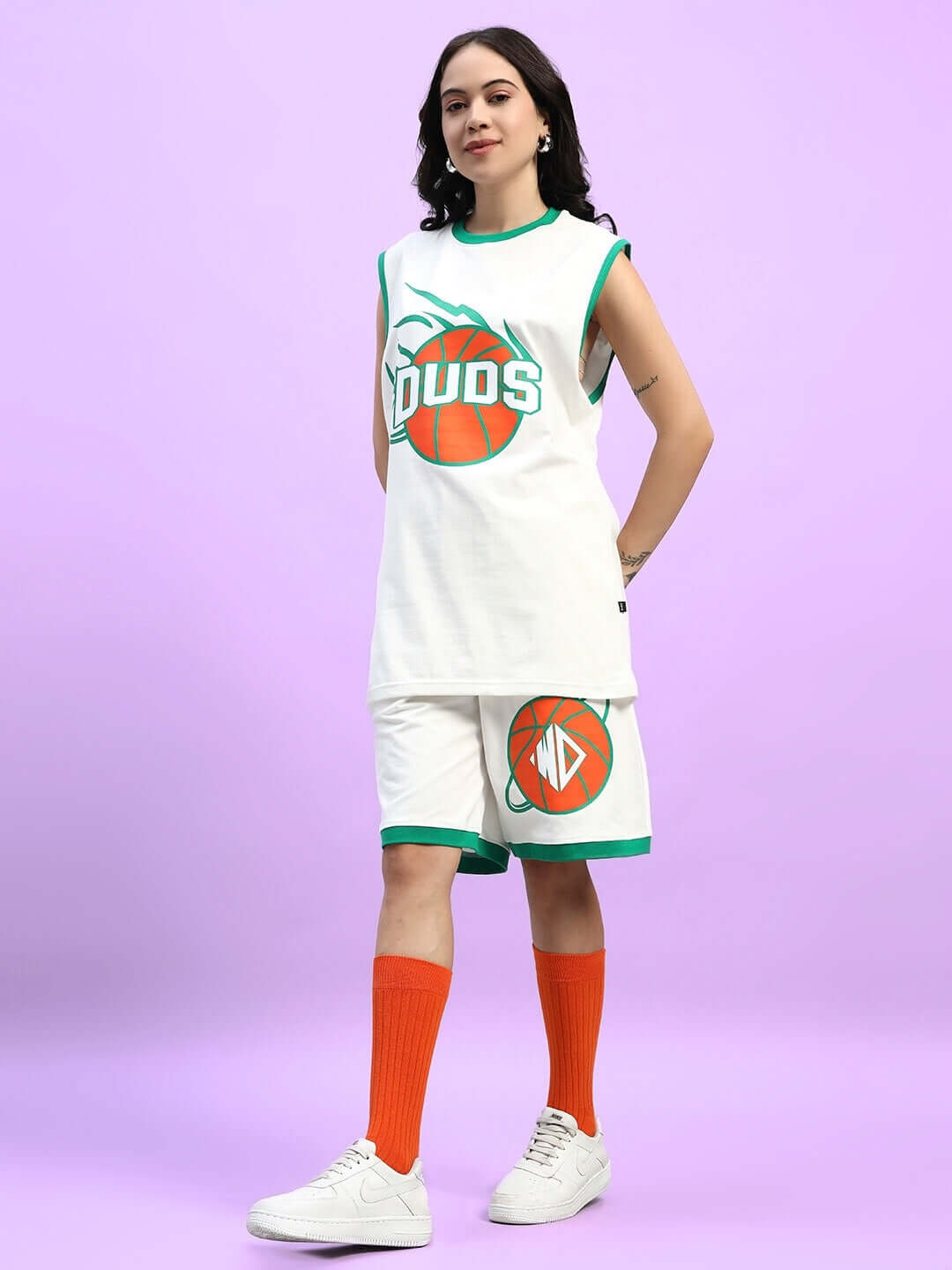 Woman wearing WOMEN'S DRIBBLE CO-ORD SET OFF WHITE with basketball graphic against purple backdrop.