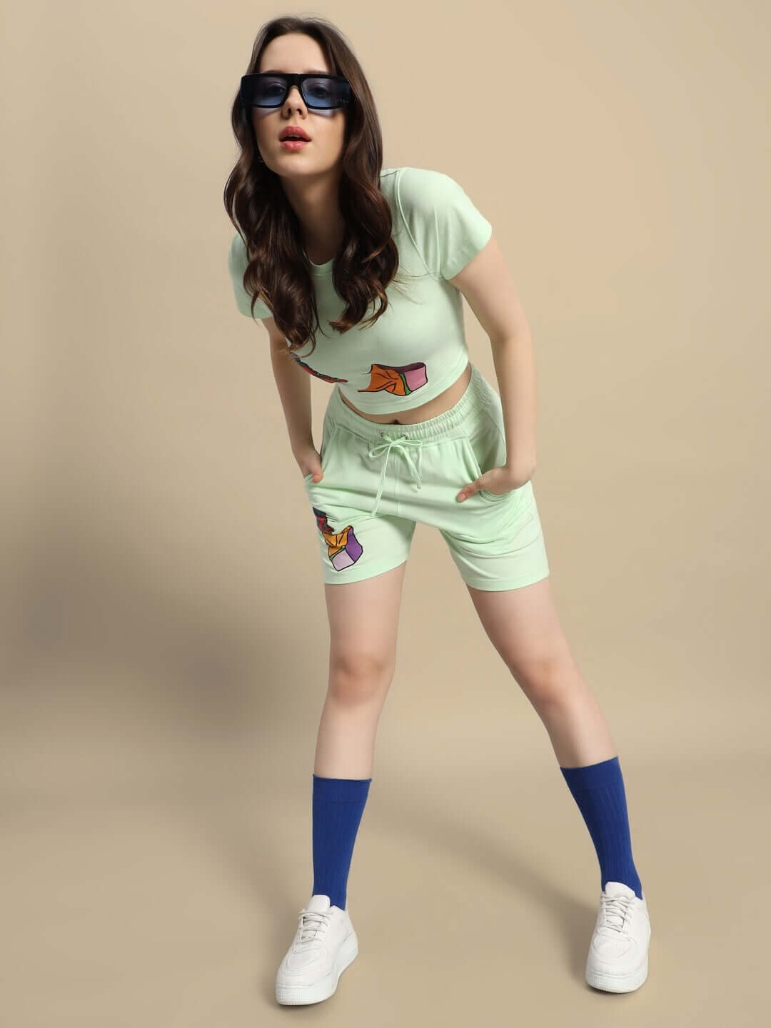 Model wearing Women's Drip God Co-ord Set in Nyanza Green, featuring print design, styled with sunglasses and sneakers against a neutral backdrop.