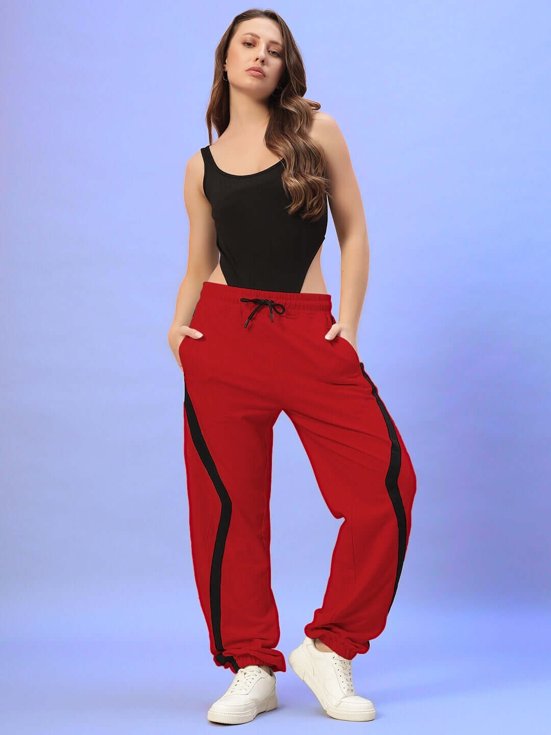 Red women's joggers by DUDS featuring a relaxed fit and customizable size options, worn by a model in a black top and white sneakers.