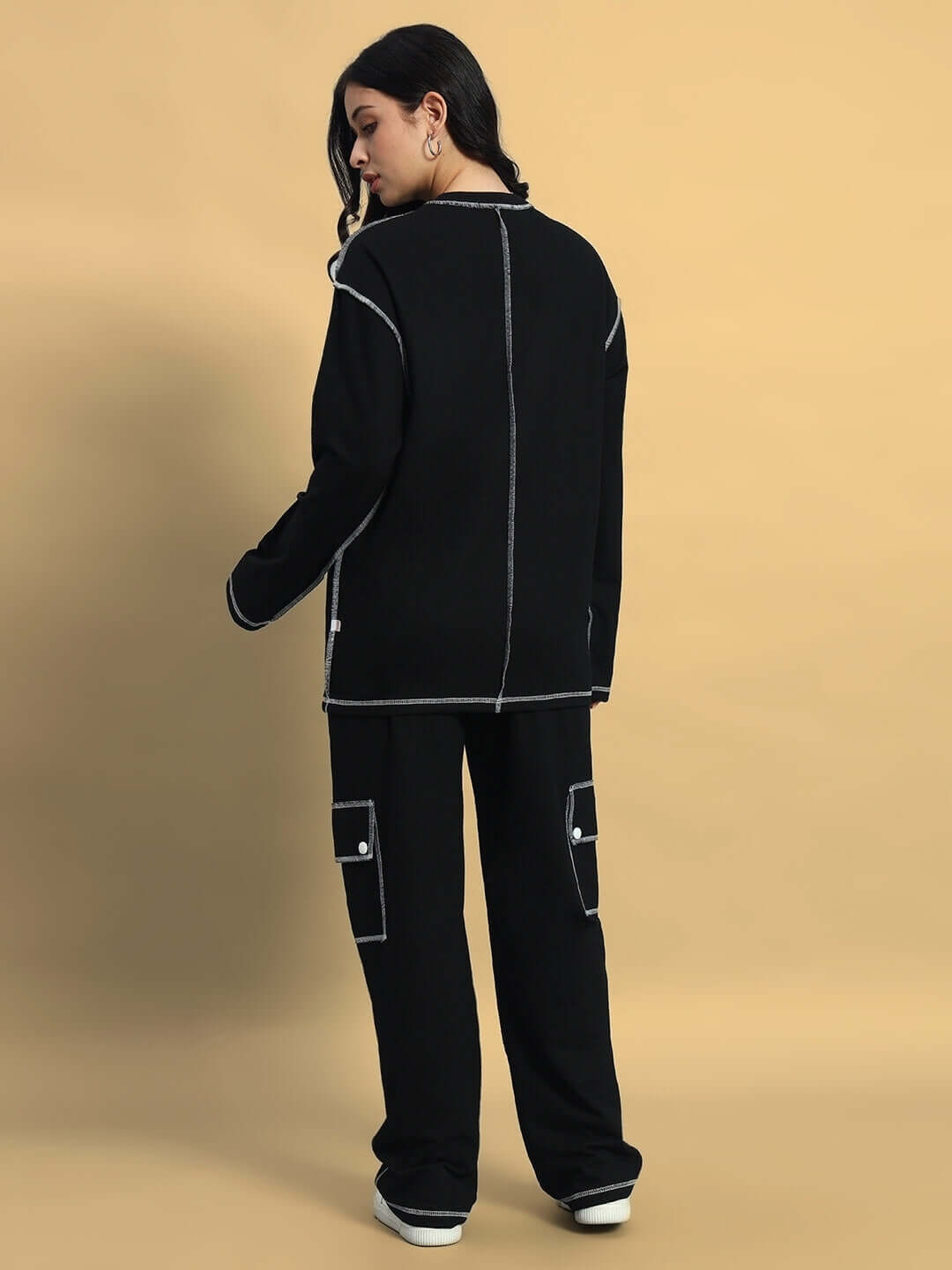 Woman wearing oversized black co-ord set with contrast panel joggers, featuring relaxed fit and elastic waistband for customizable comfort.