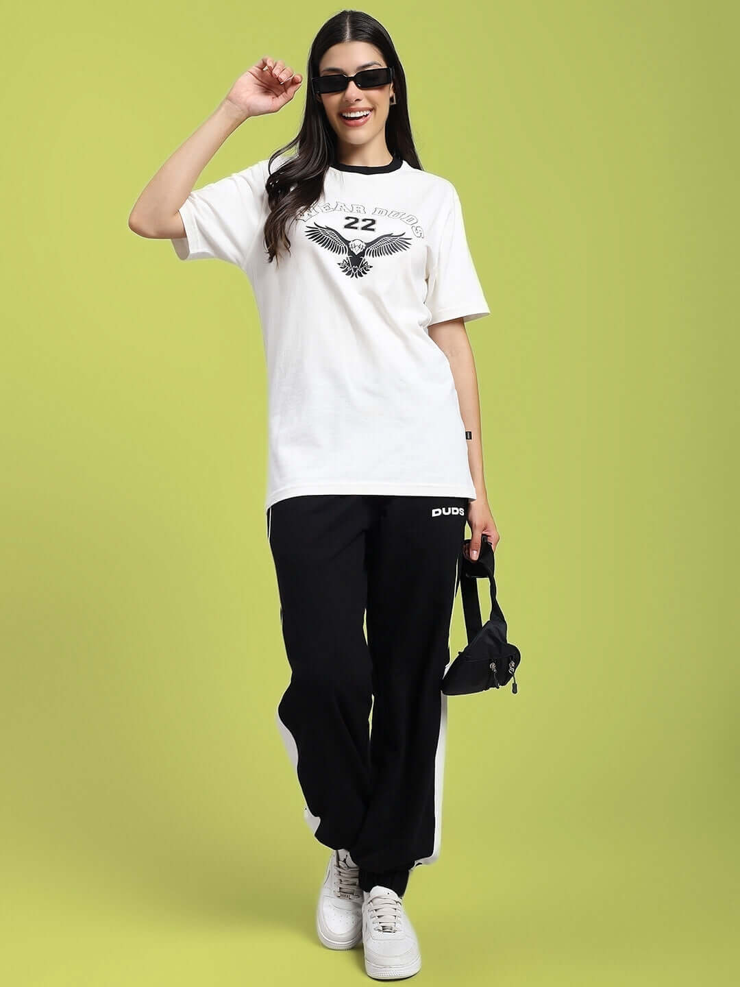 Woman wearing Women's Eagle Wings Regular Fit T-shirt in white, paired with black pants and white sneakers, posing confidently.