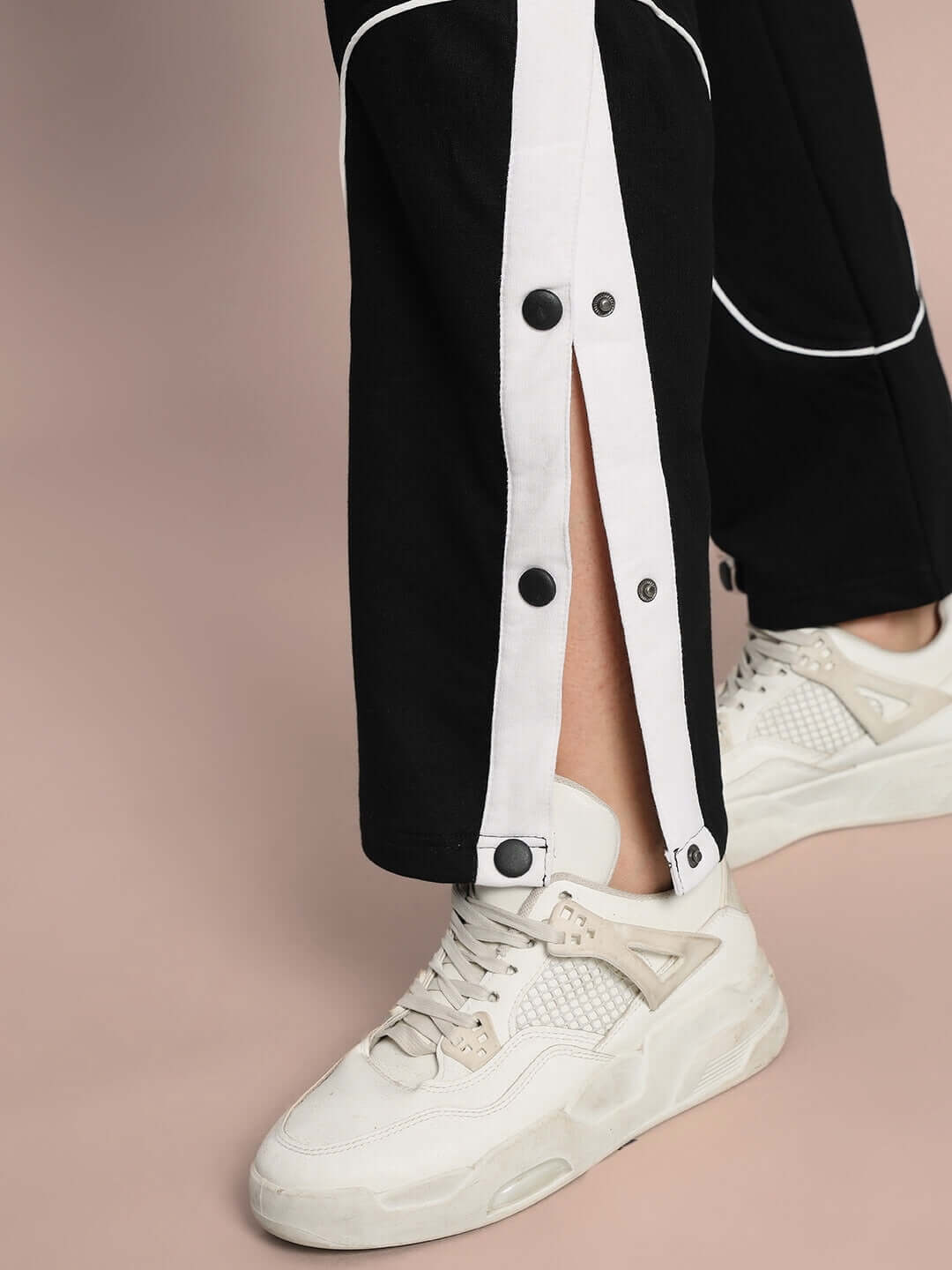 Close-up of Women's Eddie Contrast Joggers in black with white buttons and casual sneakers.