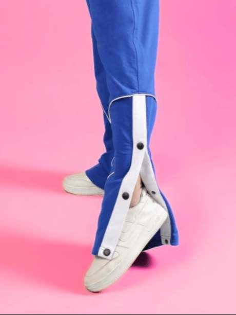 Women's blue Eddie contrast joggers with buttoned side detail, paired with white sneakers on a pink background.