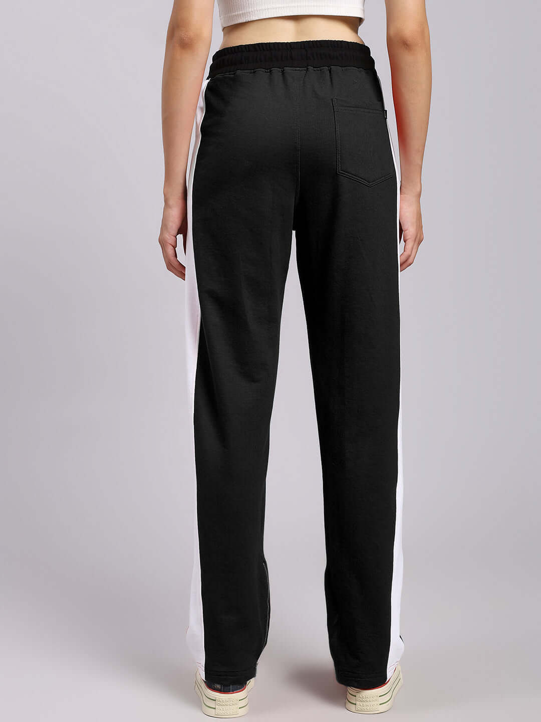 Back view of women's elegant black relaxed-fit joggers with white side stripe, showcasing comfortable and stylish design.