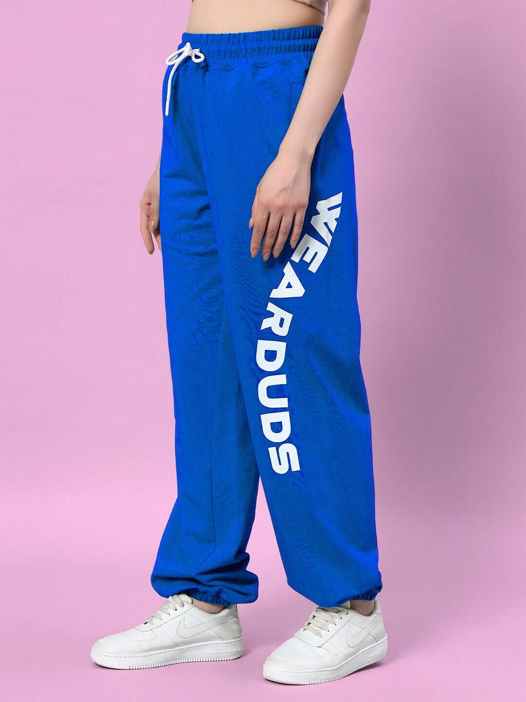 Model wearing blue women's jogger with 'WEARDUDS' text, featuring a relaxed fit and customizable options, part of DUDS collection.