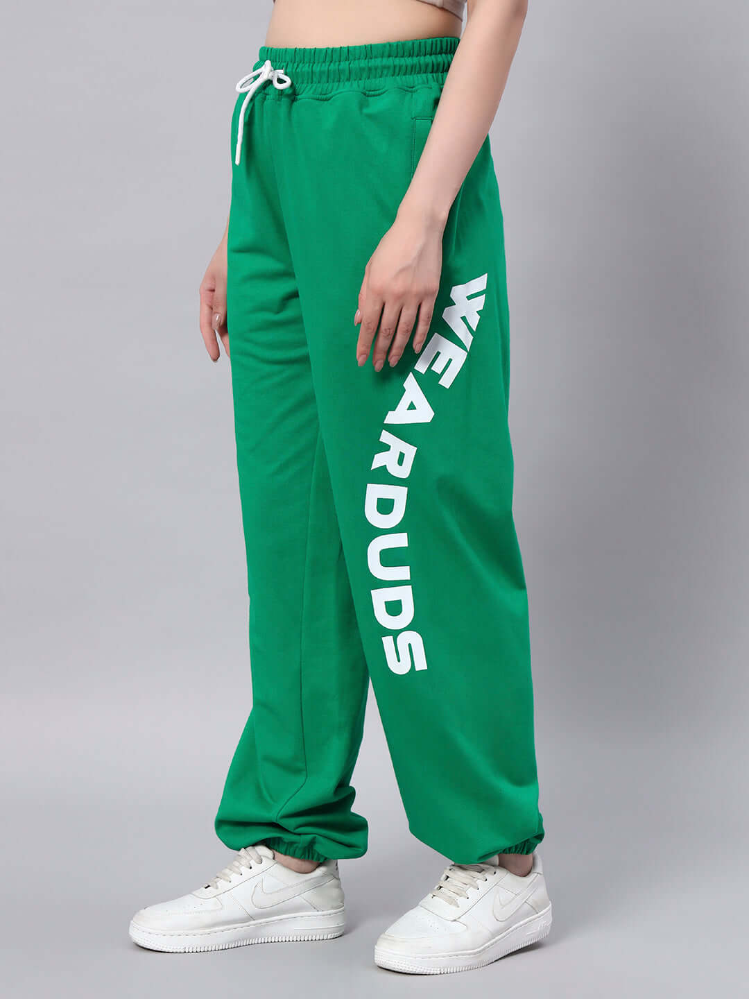 Women's Ellen Relaxed Fit Jogger Green with 'WE ARE DUDS' text on leg, worn by model in white sneakers, tailored by Duds Tailors.