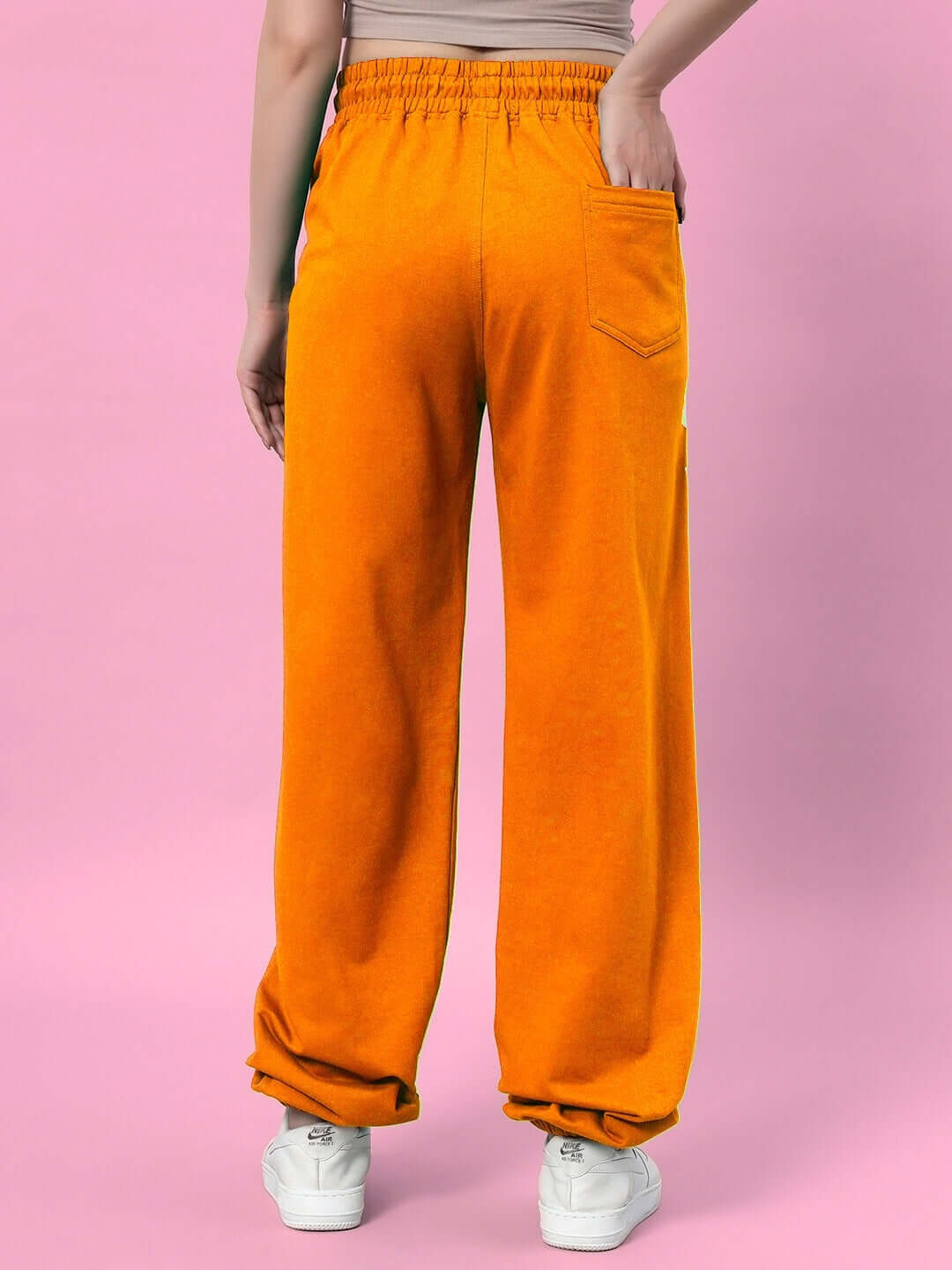 Back view of WOMEN'S ELLEN RELAXED FIT JOGGER ORANGE against a pink background