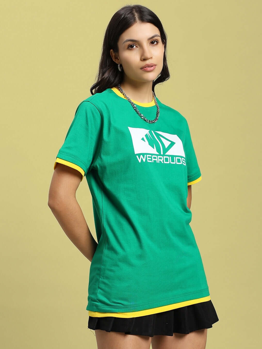 Model wears a green women's regular fit t-shirt with logo, crafted from premium bio-washed cotton, styled with black skirt.