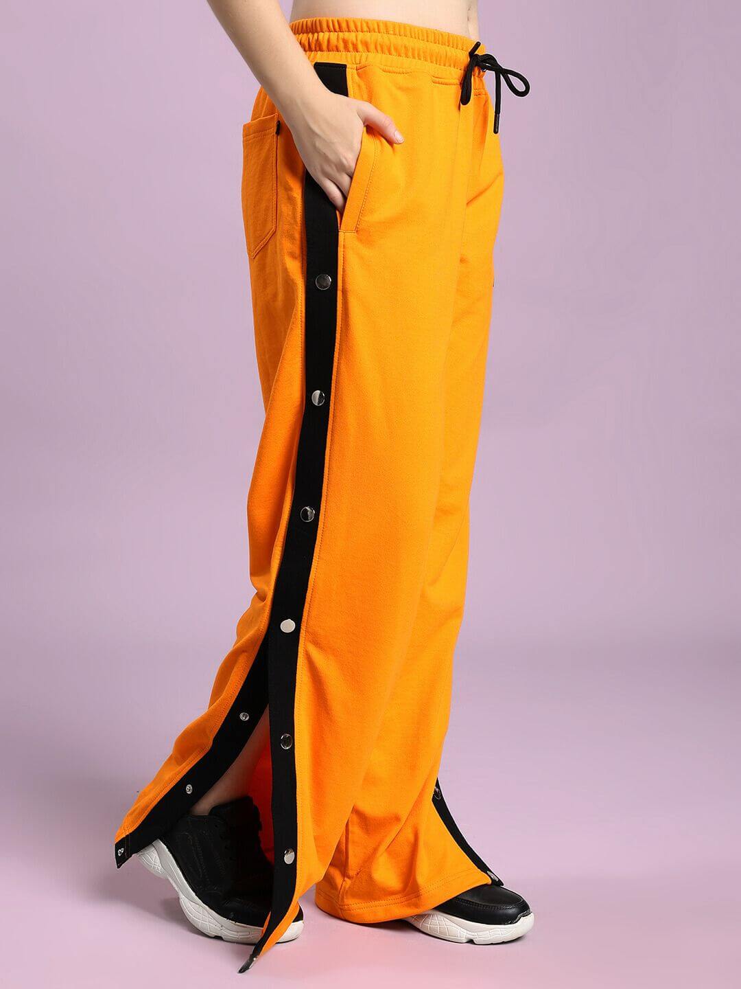 Model wearing WOMEN'S EMBER BOLT SIDE JOGGER ORANGE with side stripe and buttons, vibrant and stylish for casual wear.