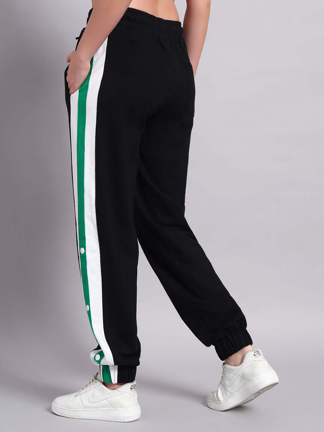Back view of a woman wearing black joggers with green and white Emirati stripes, paired with white sneakers. Ideal for custom fit orders.