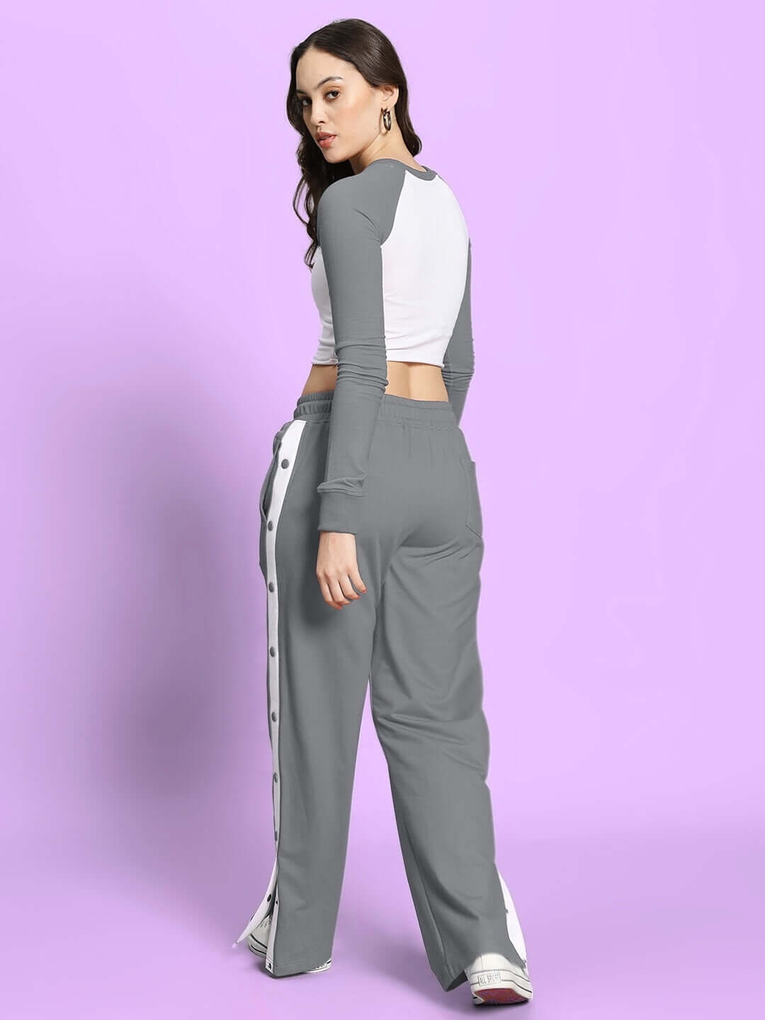 Woman wearing grey and white Ezel co-ord set with relaxed fit joggers and elasticated waistband, styled on a purple background.