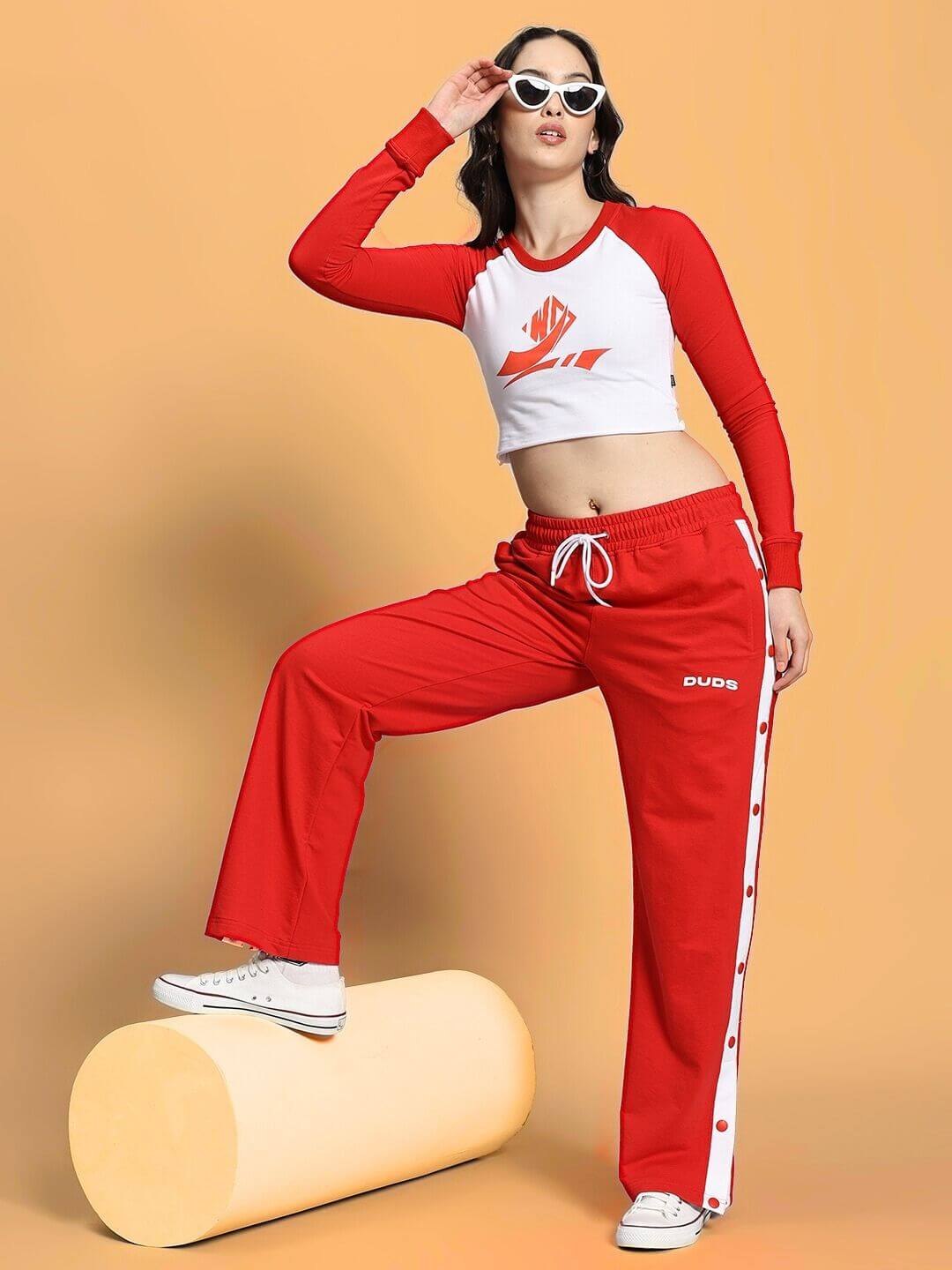 Stylish woman modeling the WOMEN'S EZEL CO-ORD SET RED-WHITE with a sporty and confident pose, showcasing bold red and white attire.