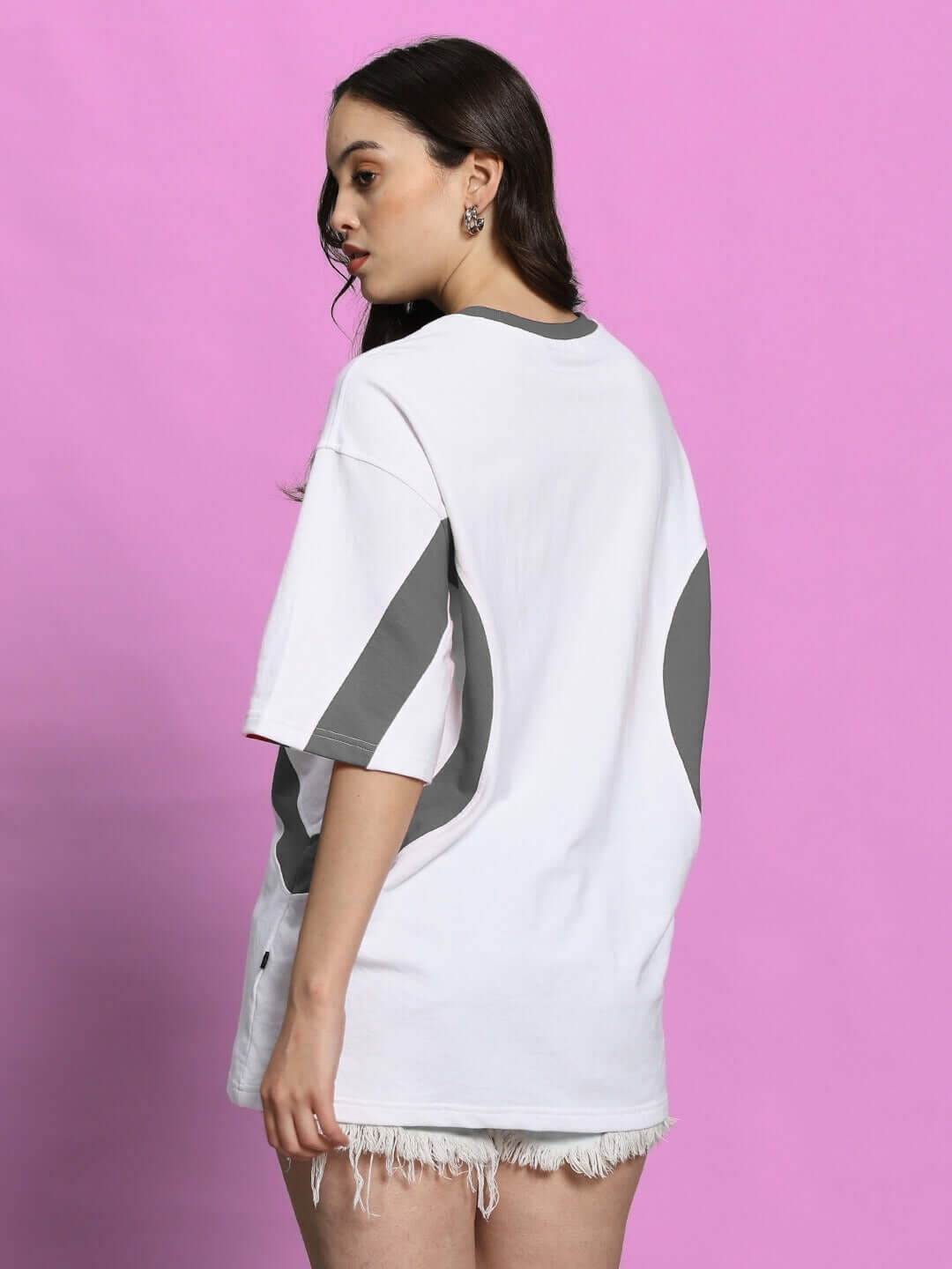 Woman wearing white-grey oversized EZEL T-shirt, premium cotton, back view, on pink background.