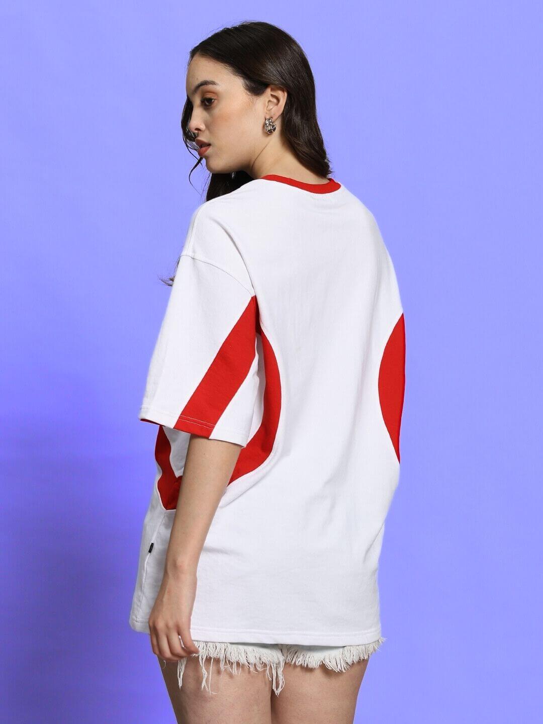 Model wearing women's oversized white-red T-shirt, premium cotton fabric, styled with casual frayed shorts.