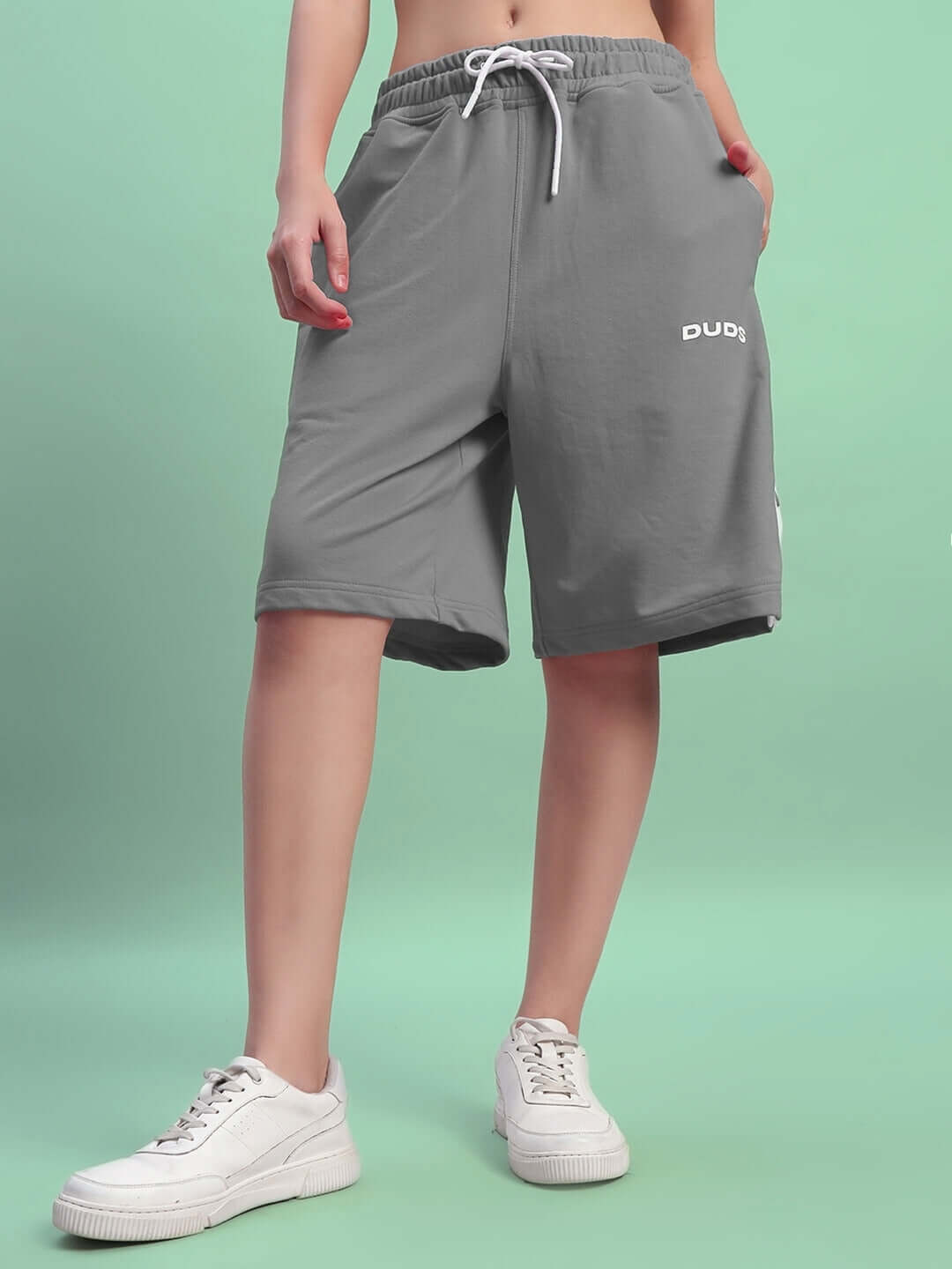 Woman wearing grey WOMEN'S EZEL REGULAR FIT SHORTS with a drawstring waist, showcasing comfortable fit and casual style.