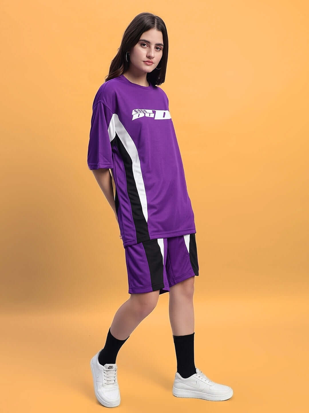 Model wearing Women's FIFA Colorblock Co-Ord Set Purple with sporty, vibrant design from WEAR DUDS on an orange background.