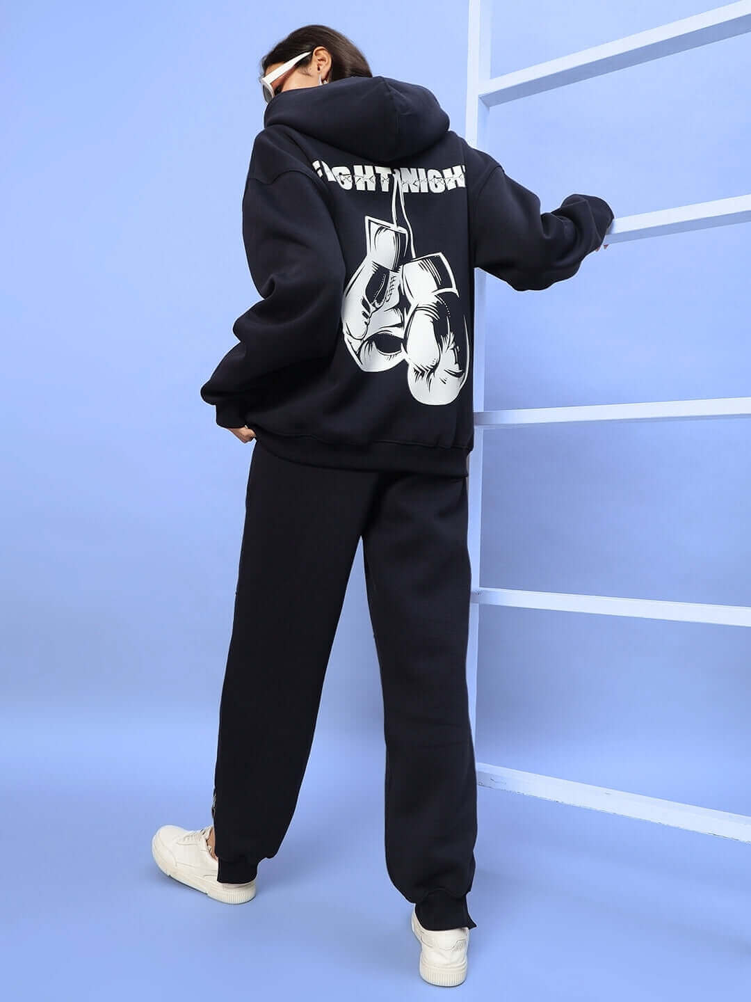Woman wearing navy blue fleece co-ord with Fight Night graphic on hoodie, posing against a blue backdrop.