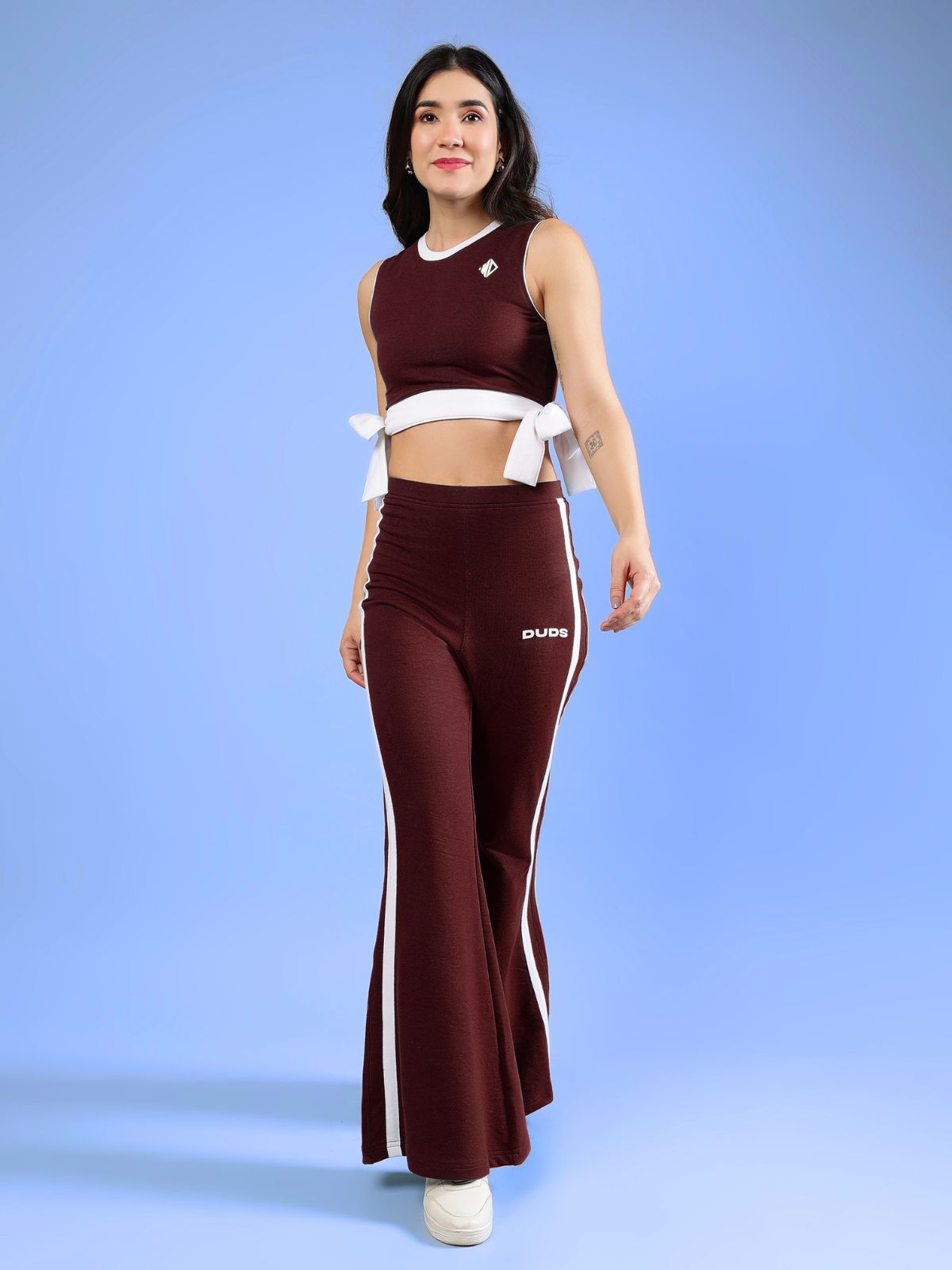 WOMENS FITTONIA COOL CO-ORD SET MAROON modeled by a woman with a sporty look against a blue background.