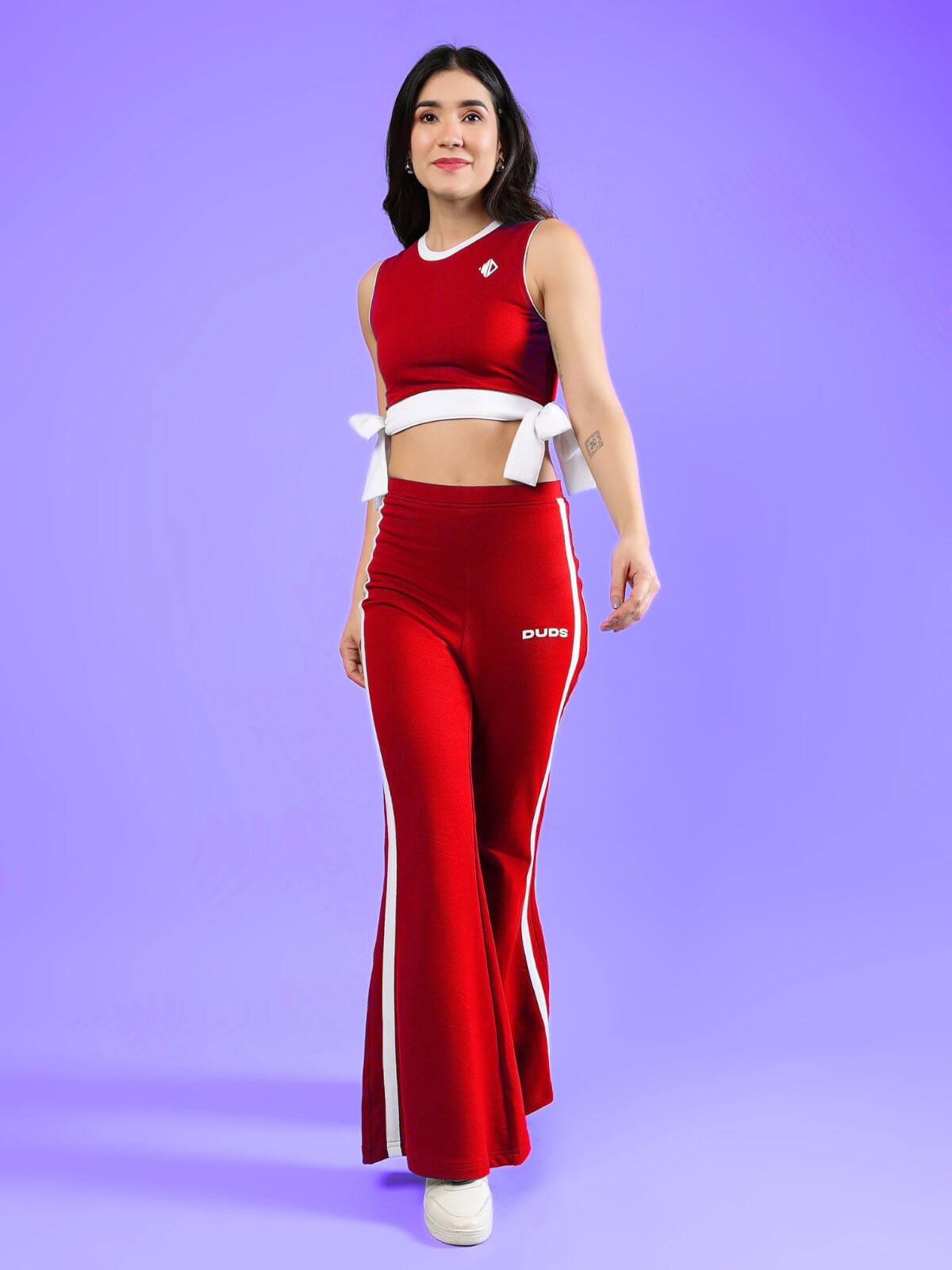 WOMENS FITTONIA COOL CO-ORD SET RED worn by a model, showcasing a stylish red two-piece outfit against a vibrant purple background.