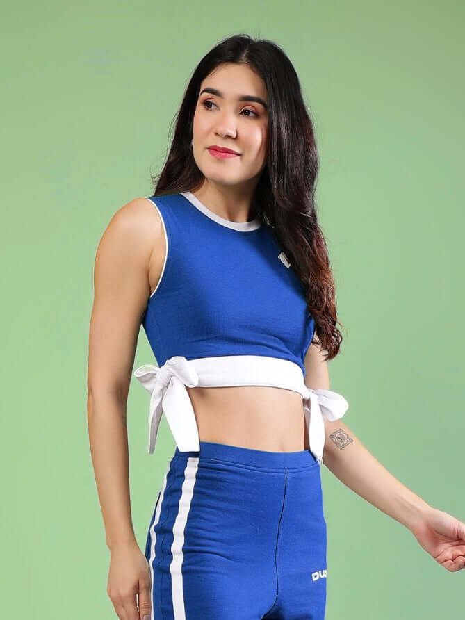 WOMENS FITTONIA COOL CROP TOP BLUE model wearing sporty blue crop top with white ties, perfect for casual wear and workouts.