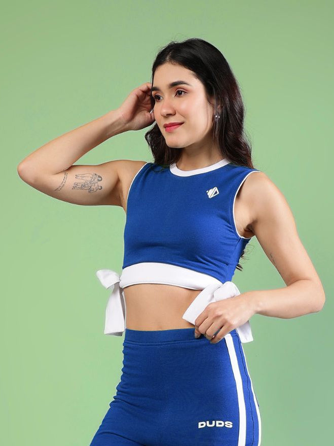 WOMENS FITTONIA COOL CROP TOP BLUE worn by a model, showcasing sporty style in vibrant blue color.