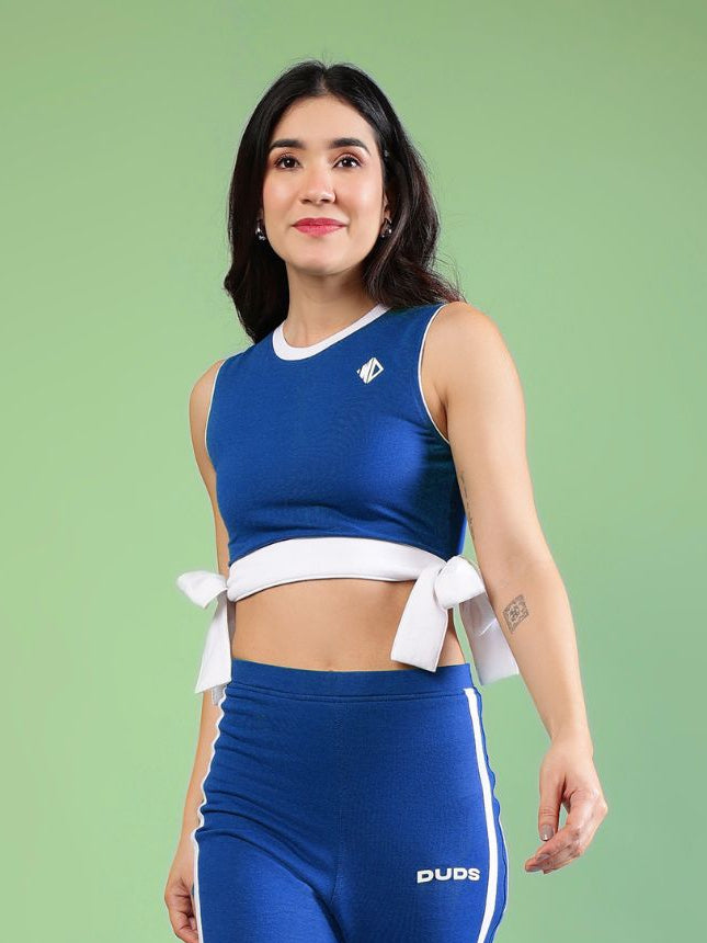 WOMENS FITTONIA COOL CROP TOP BLUE worn by a woman, showcasing sporty style and vibrant blue color.