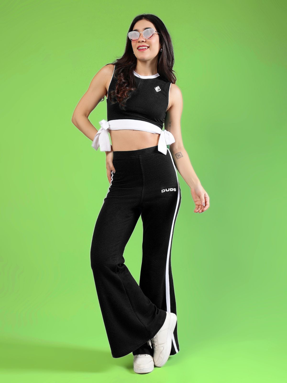 WOMENS FITTONIA COOL WIDE FLARE JOGGERS BLACK worn by a model against a bright green background, showcasing style and comfort.