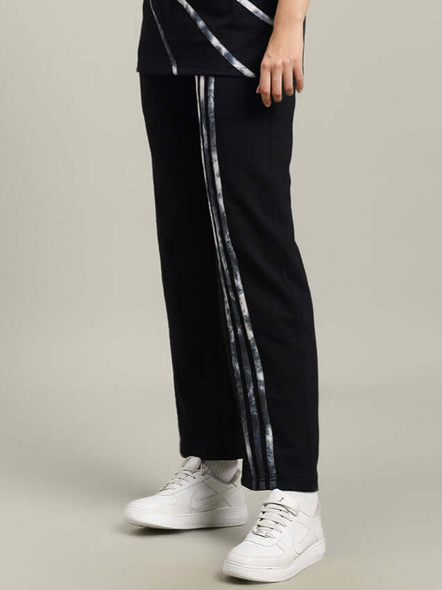WOMEN'S FLICKER JOGGER COTTON TERRY BLACK with stripe detail, displayed on model with white sneakers.