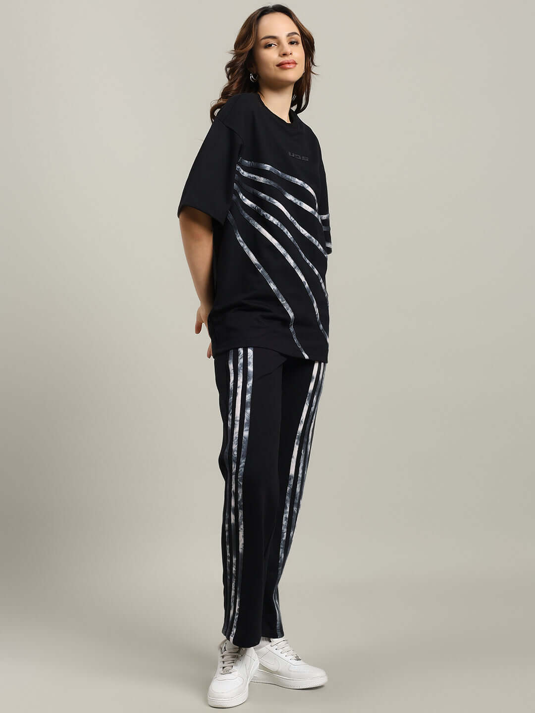 Model wearing WOMEN'S FLICKER OVERSIZED CO-ORD SET BLACK with relaxed fit joggers and stylish t-shirt, showcasing elasticated waistband and drawstring.