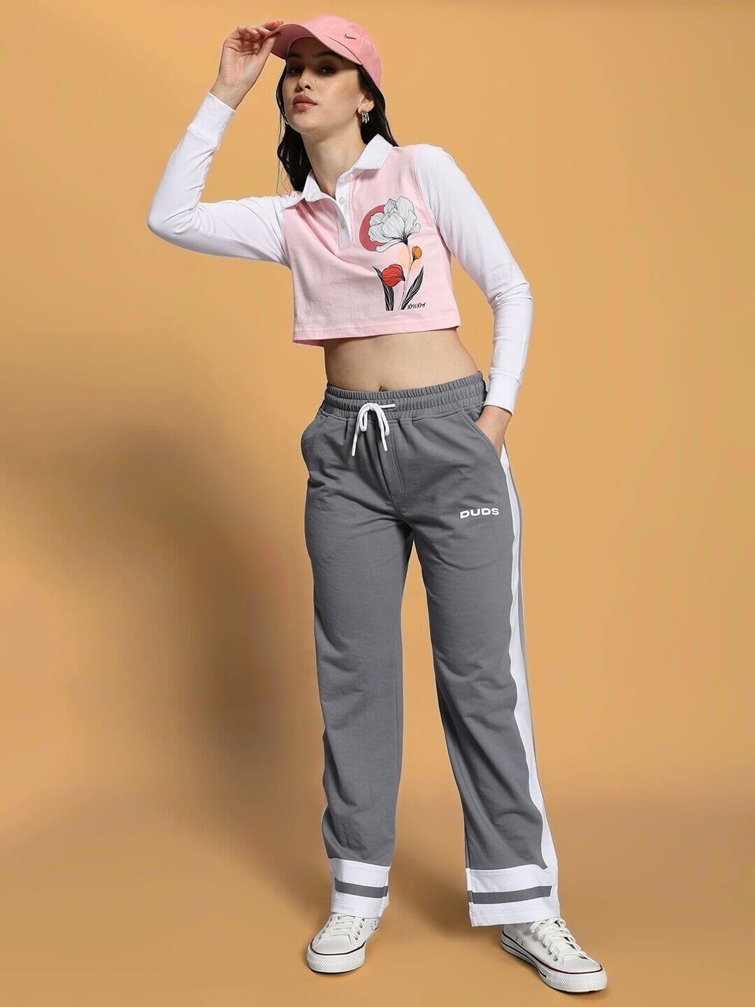 Model wearing WOMEN'S FLORA CO-ORD SET PINK GREY with floral top and grey pants, styled with pink cap and sneakers for a chic streetwear look.