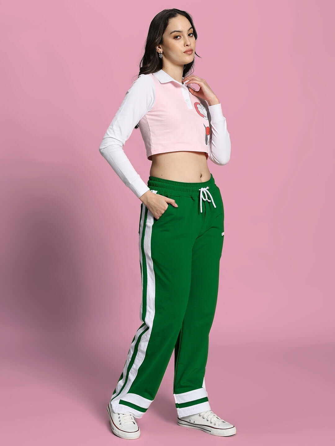 Woman wearing WOMEN'S FLORA CO-ORD SET PINK GREEN, featuring a pink top and green pants, standing against a pink background.