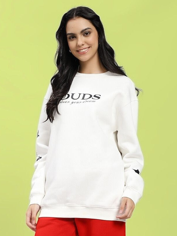 Woman wearing WOMEN'S FLY OR DIE DRAGON PRINT FLEECE SWEATSHIRT OFF WHITE, smiling against green background.